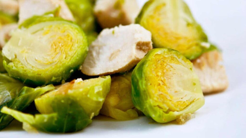 A white plate with Chicken And Brussels Sprouts on it.