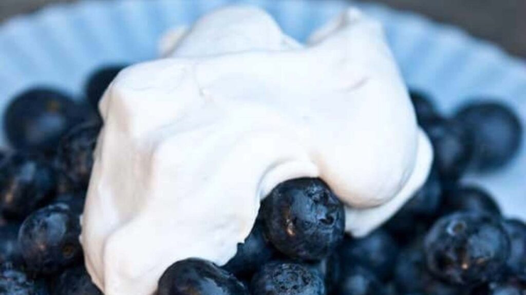 A dollop of whipped cream over fresh blueberries.