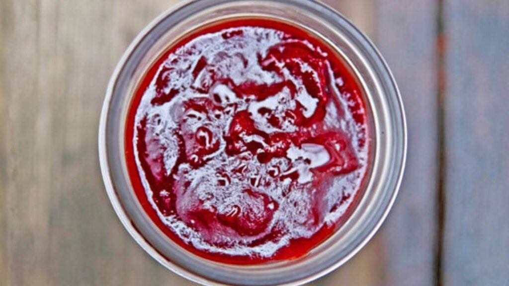 An open canning jar filled with cranberry butter.