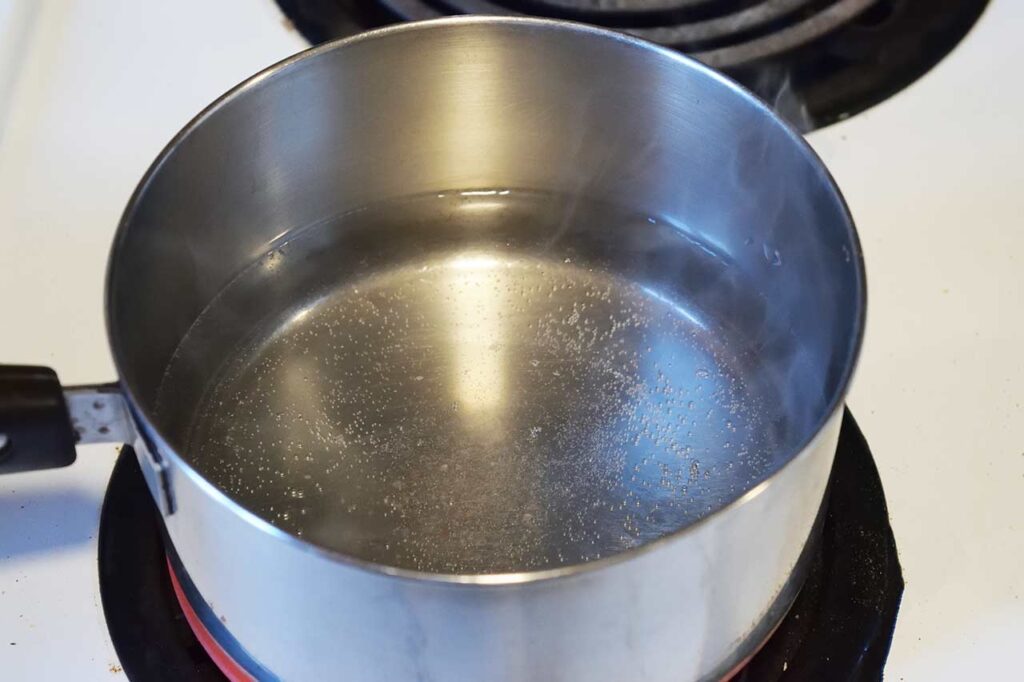 Water in a pot with a pinch of salt, coming to a boil.