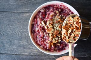 Adding chopped pecans to cranberry oatmeal.