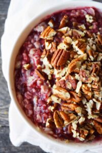 An overhead partial view of a white bowl filled with Cranberry Oatmeal and garnished with pecans.