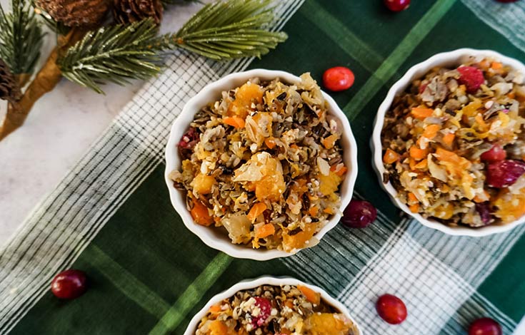 Three bowls on a tabletop filled with cranberry squash casserole.