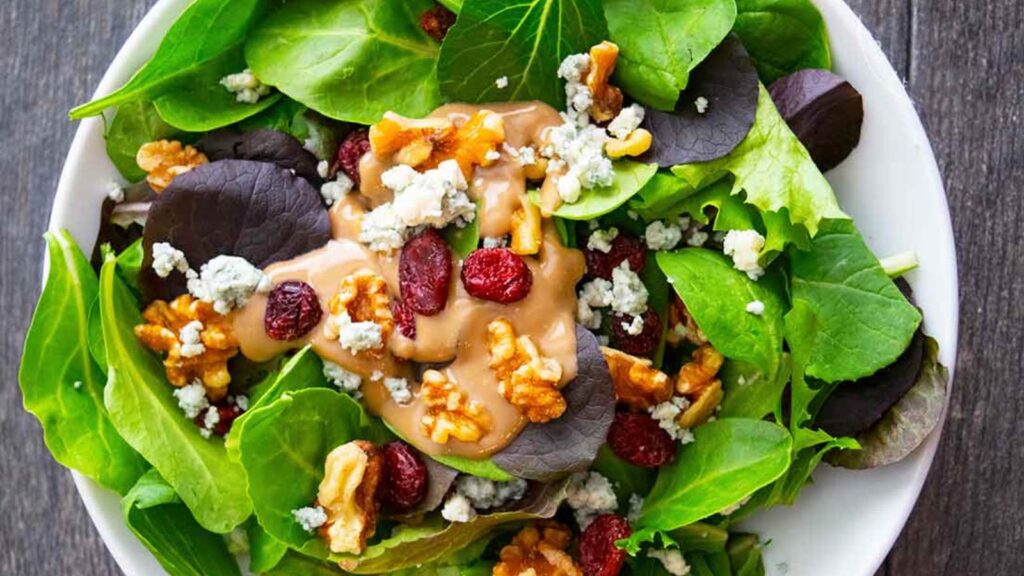 An overhead view of a white bowl filled with cranberry walnut salad.