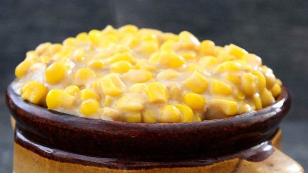 A closeup of a crock filled with creamed corn.