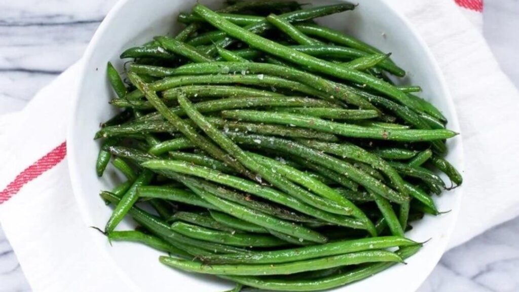 A white bowl filled with green beans.