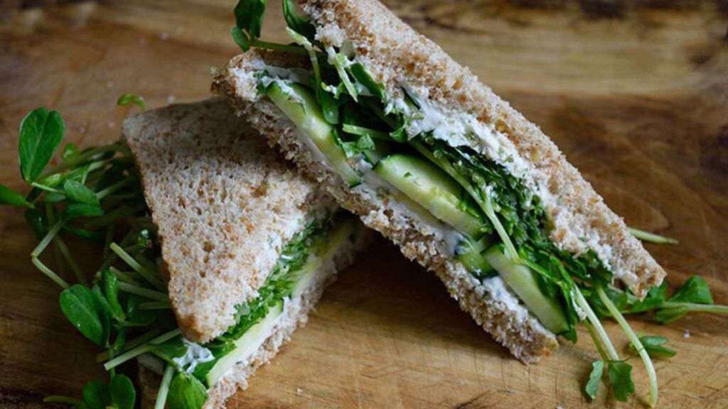 A finished cucumber sandwich cut in half.