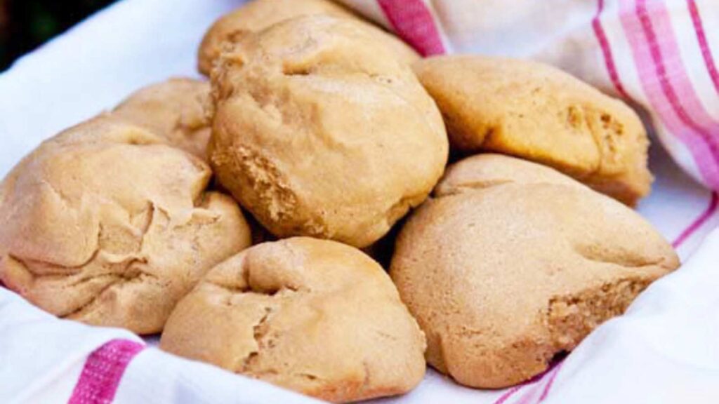 A towel-lined basket of dinner rolls.