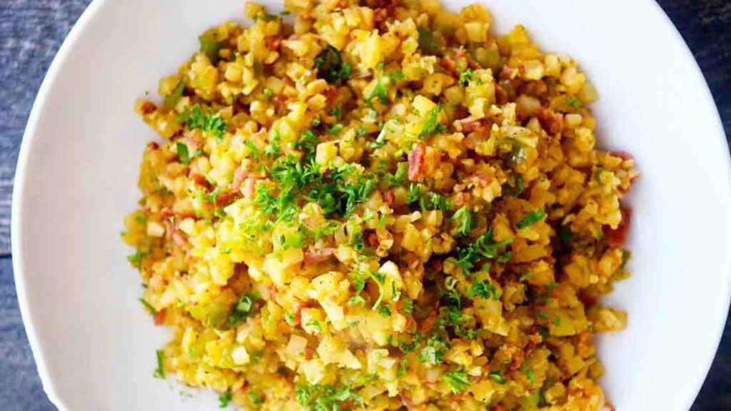 An overhead shot of a while bowl filled with this Dirty Cauliflower Rice Recipe and garnished with chopped, fresh parsley.