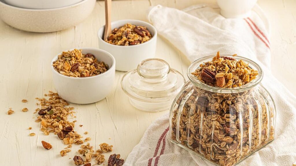 a jar and two bowls filled with vegan, gluten-free granola.