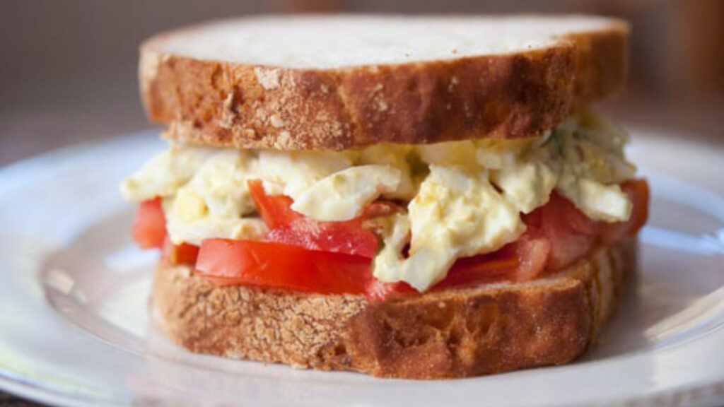 An Egg Salad Sandwich sitting on a white plate.