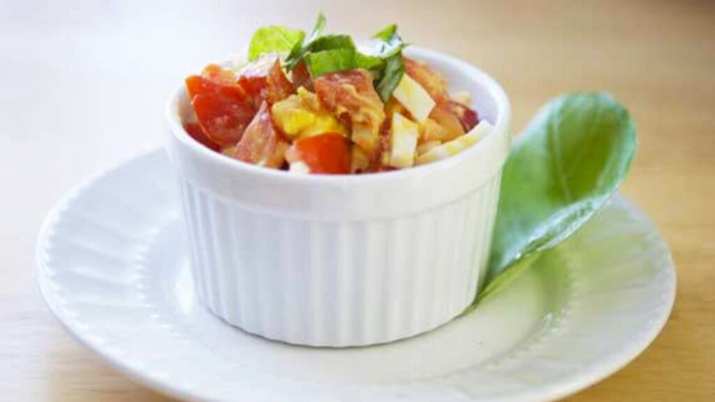 A white bowl filled with egg and tomato salad.