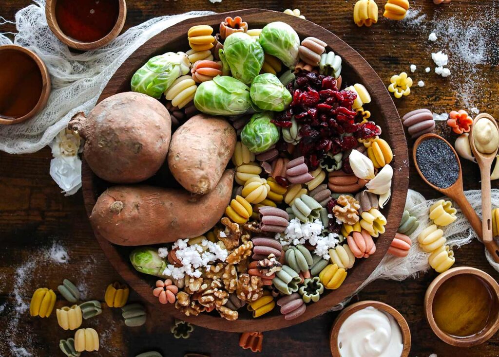 All the Fall Harvest Pasta Salad Recipe ingredients gathered together in a large wood bowl.