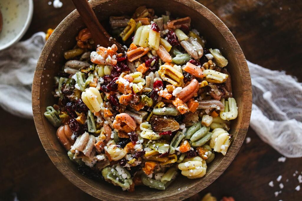 An overhead view of a Fall Harvest Pasta Salad, ready to eat, still sitting in a mixing bowl.