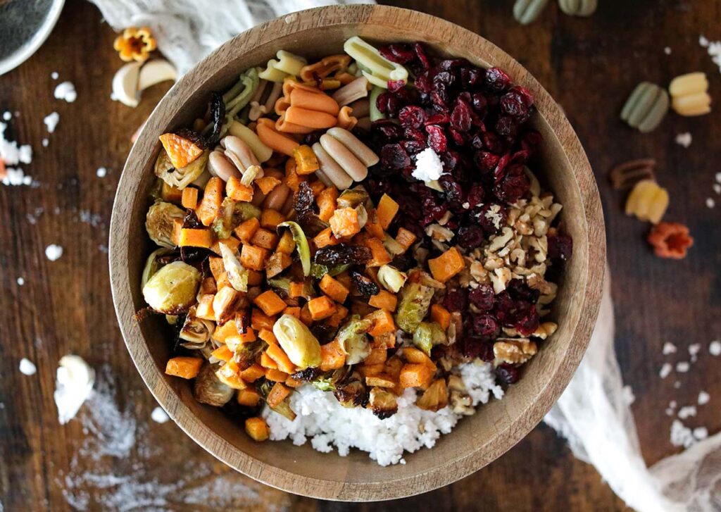 The salad ingredients all sitting together in a wood mixing bowl.