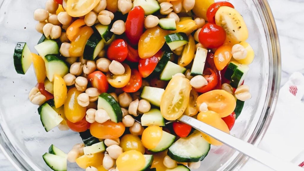 An overhead view of a chickpea salad with cucumbers and halved grape tomatoes.