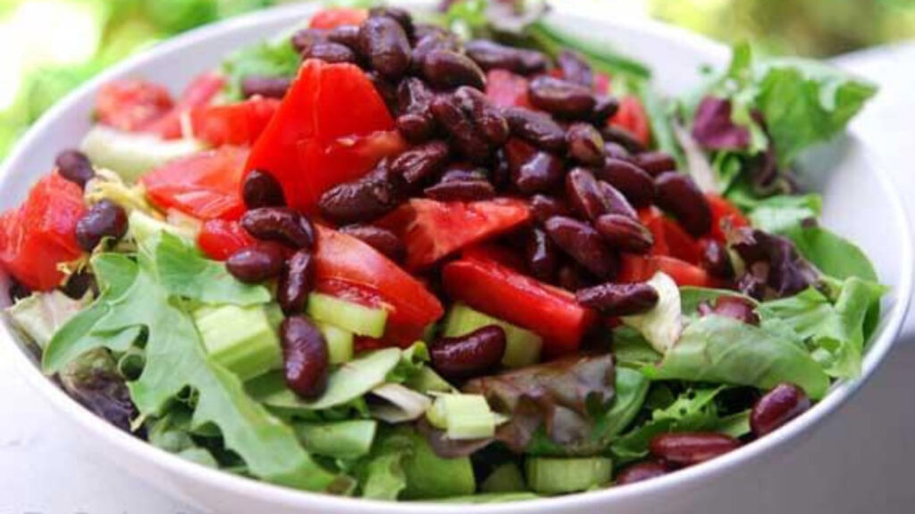 A white bowl filled with a garden salad that includes kidney beans.