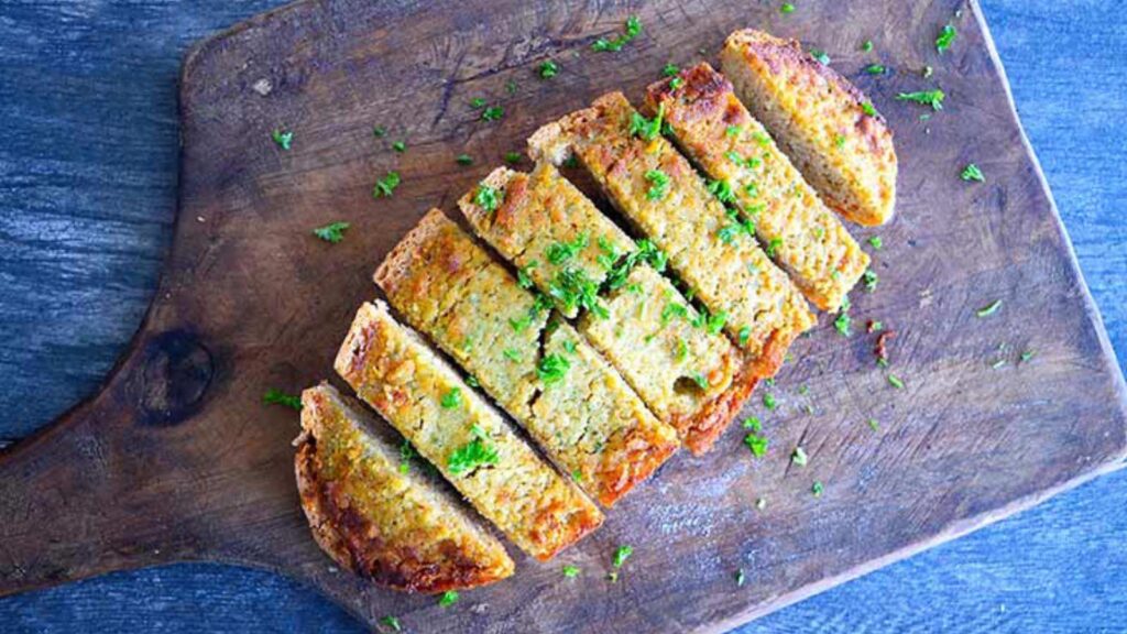 A half loaf of Garlic Bread sliced on a cutting board.