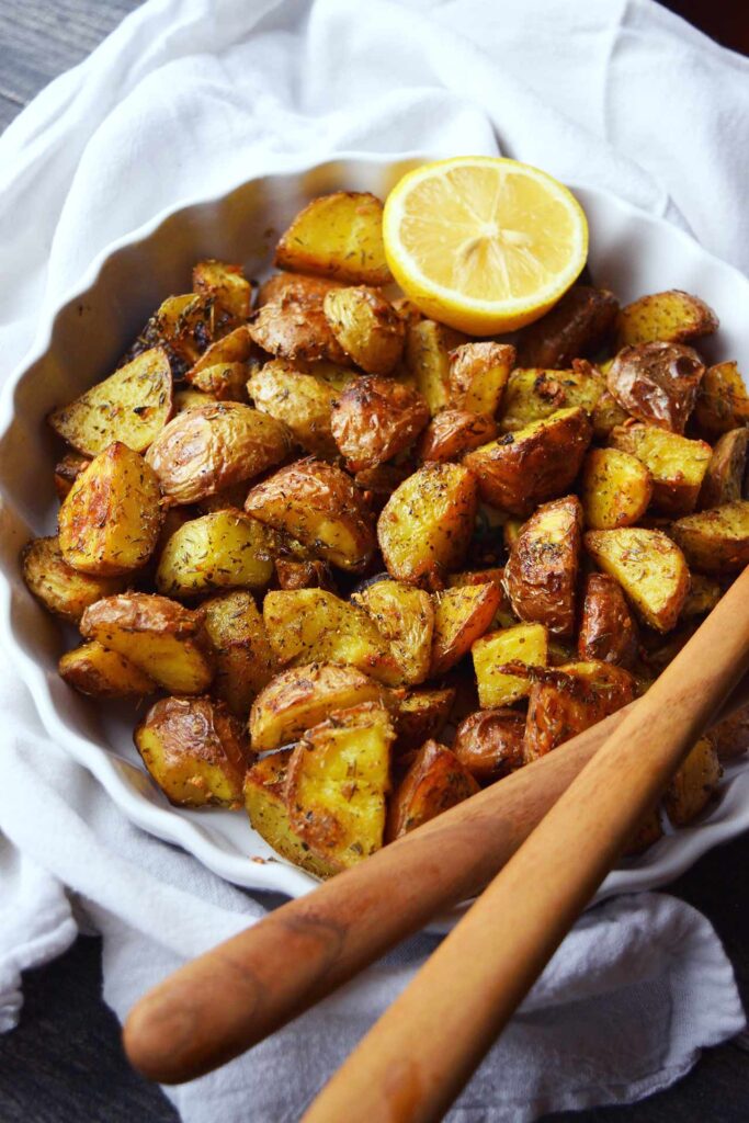 A side view of a white dish filled with Garlic Lemon Potatoes.