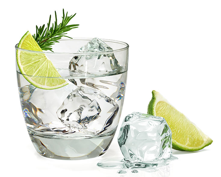 A glass of gin with a lime wedge on a white background.
