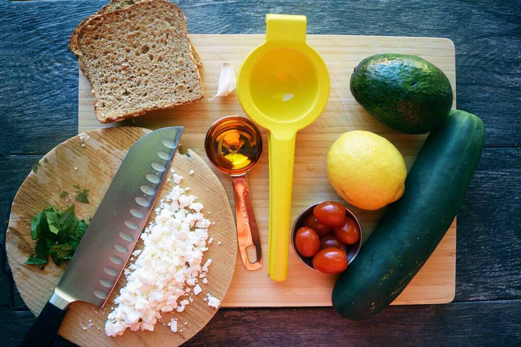 Greek Avocado Toast Recipe ingredients collected on a cutting board.