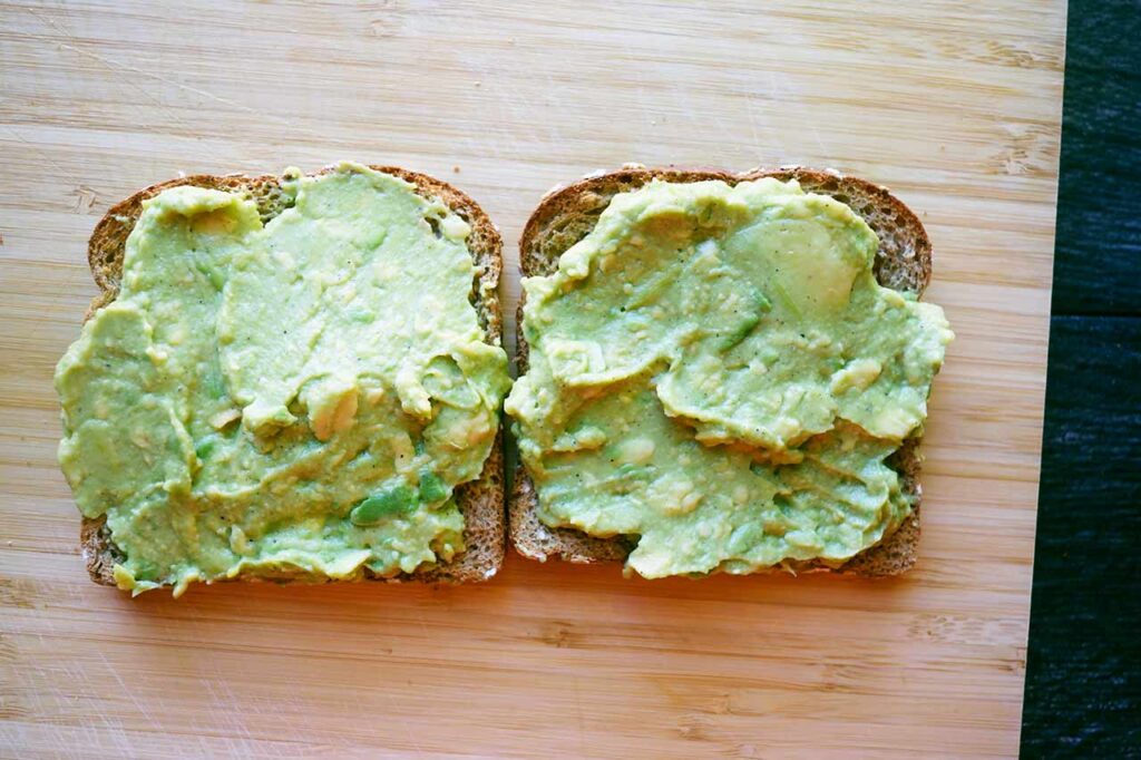 Two slices of toast with avocado spread over them.