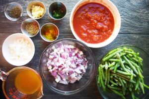 Greek Green Beans Recipe ingredients gathered in individual bowls.