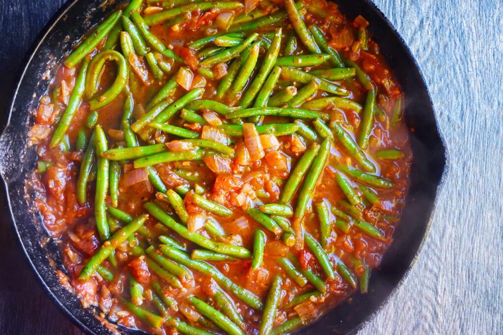 Cooked Greek Green Beans in a cast iron skillet.