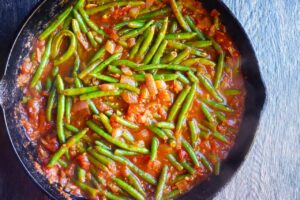 Cooked Greek Green Beans in a cast iron skillet.