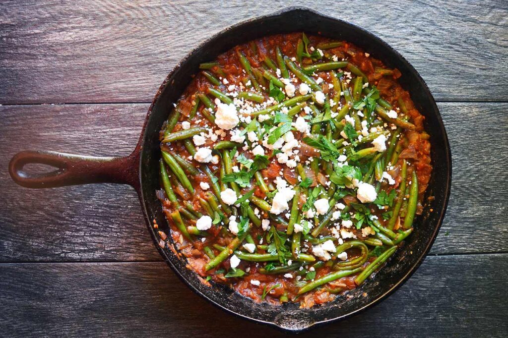 Greek green beans garnished with crumbled feta and chopped, fresh parsley.