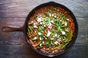 Greek green beans garnished with crumbled feta and chopped, fresh parsley.