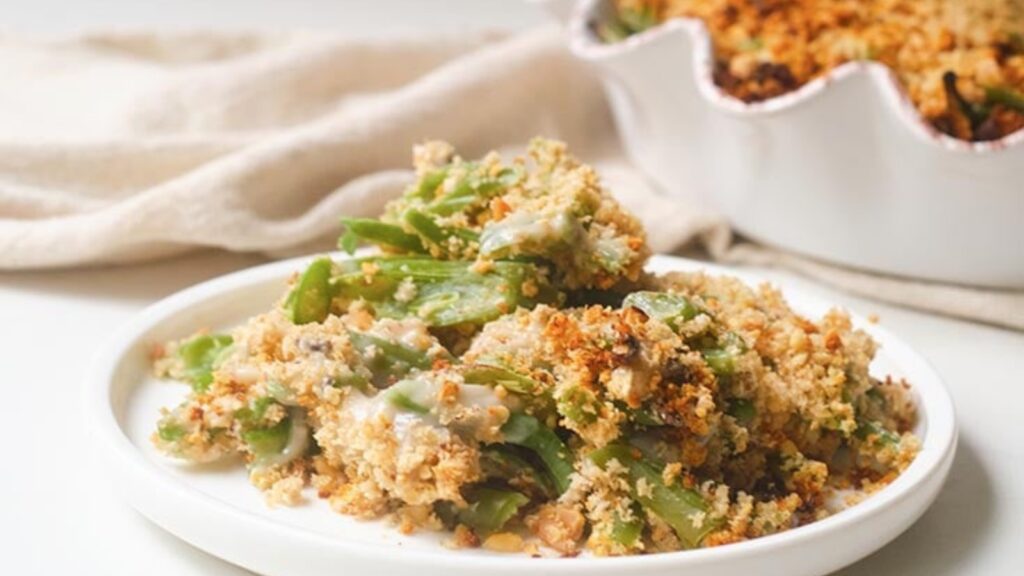 A plate of green bean casserole on a table next to the casserole dish it was baked in.