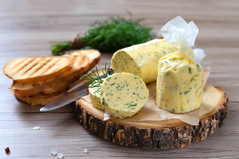 Herb butter on a cutting board with a stack of toast sitting next to it.