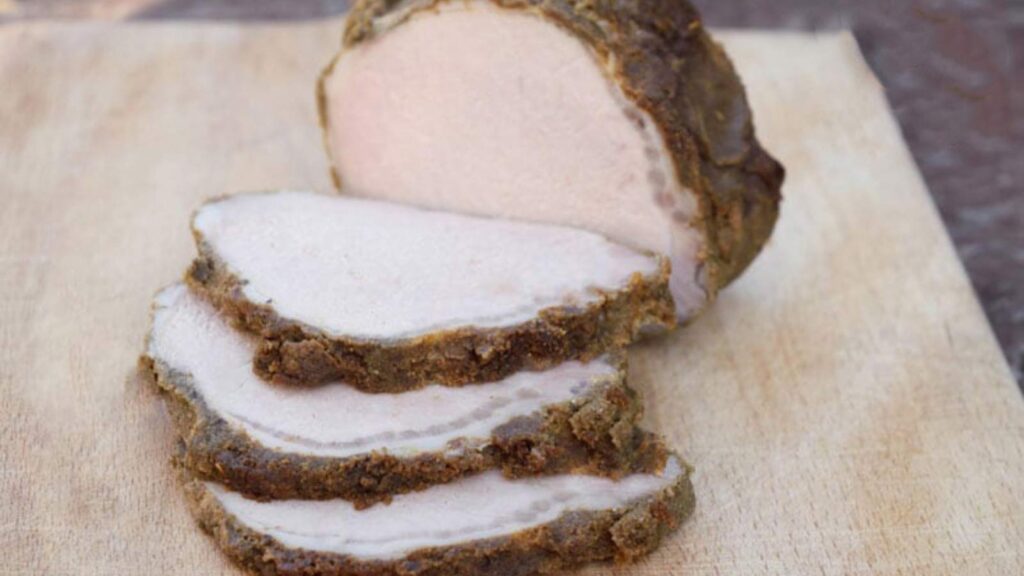 A pork loin sliced on a cutting board.