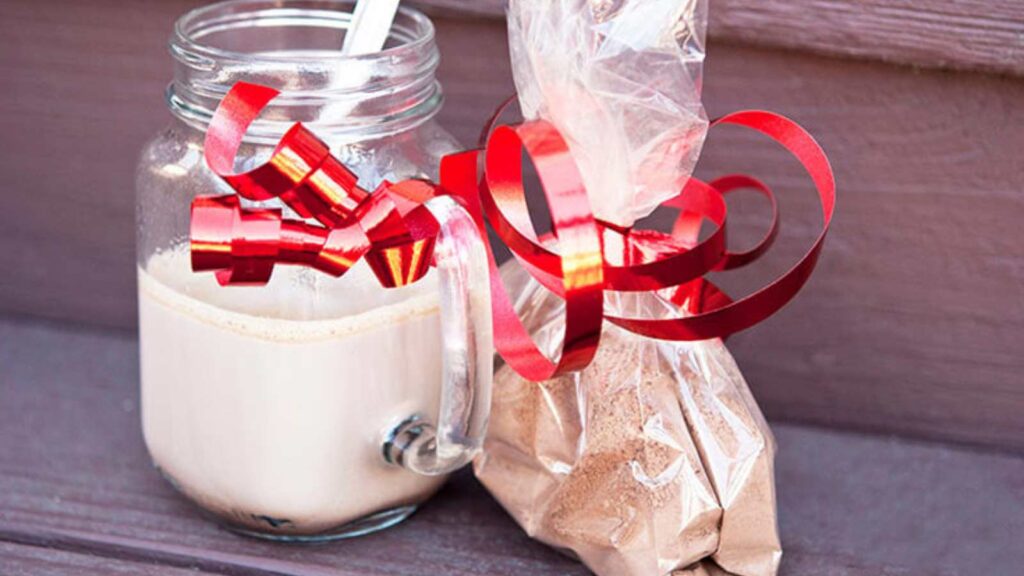 A mug of hot chocolate next to a bag of hot chocolate mix.