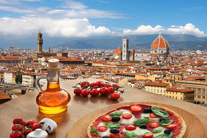 A rooftop view of Florence just beyond a table with pizza on it.
