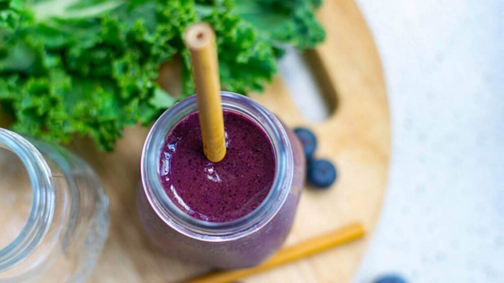 An overhead view of a glass jar filled with Kale Blueberry Smoothie.