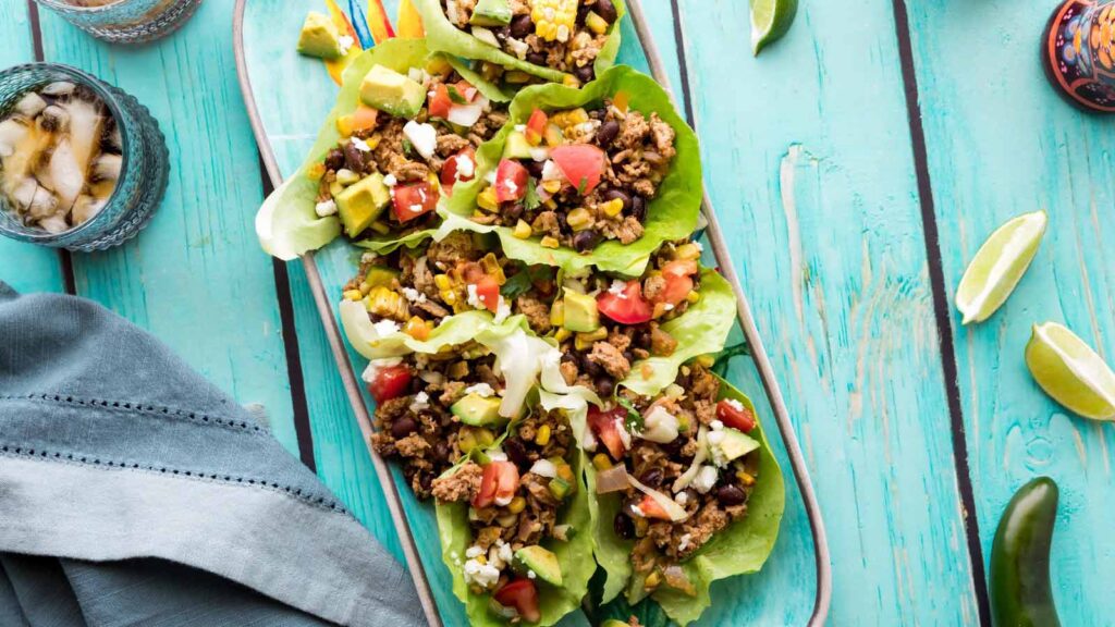 A platter of lettuce wraps sitting on a wood table.