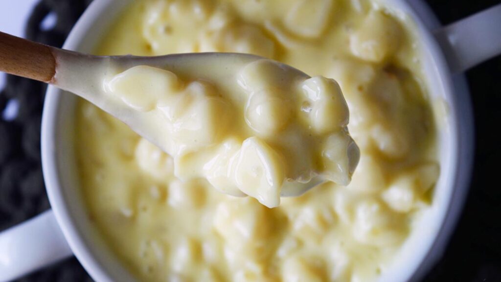 A spoon lifts mac and cheese out of a bowl.