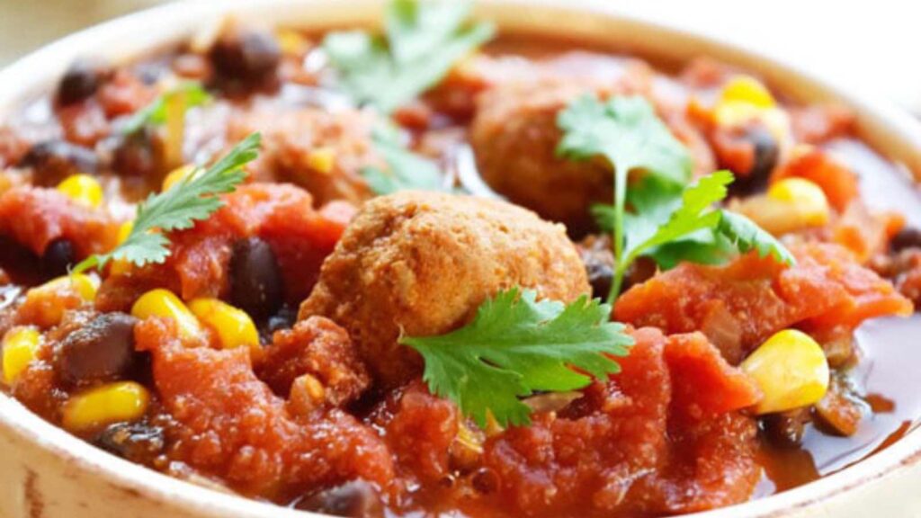 A closeup of a white bowl filled with meatball chili.