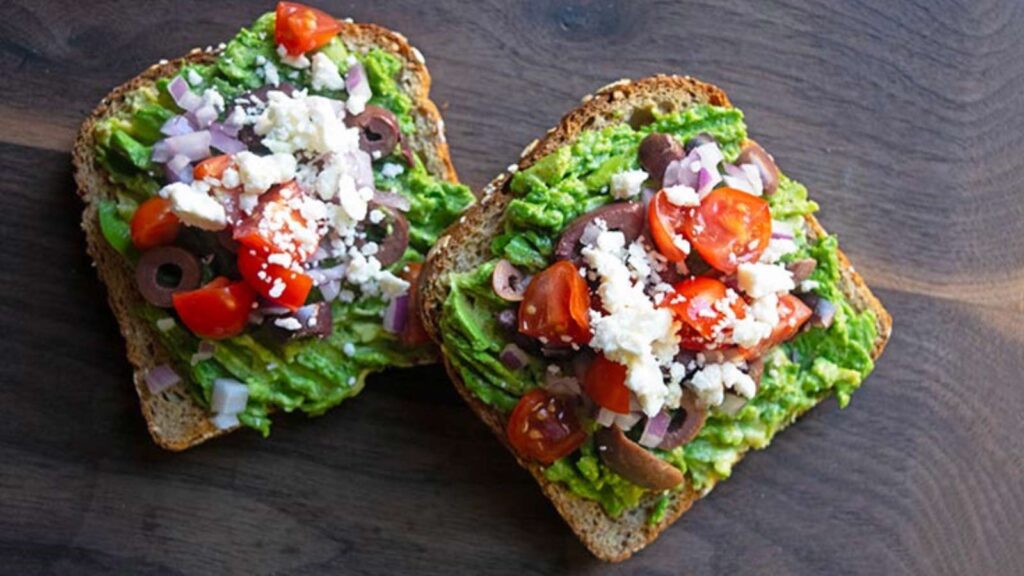 An overhead view of two slices of Mediterranean Avocado Toast.