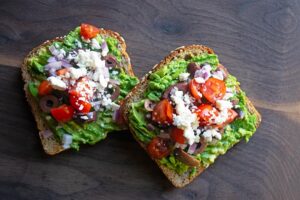 An overhead view of two slices of Mediterranean Avocado Toast.