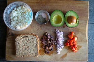 Ingredients on a cutting board for this Mediterranean Avocado Toast Recipe.