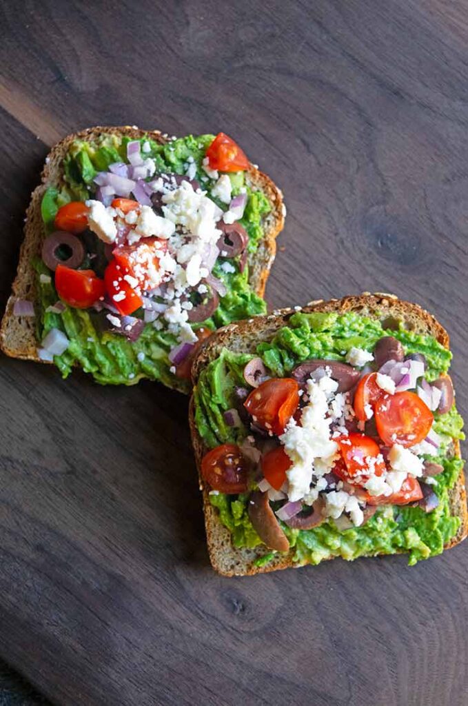 An overhead view of two slices of Mediterranean Avocado Toast.