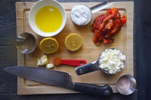 Mediterranean Roasted Red Pepper Dip Recipe ingredients laid out on a cutting board.