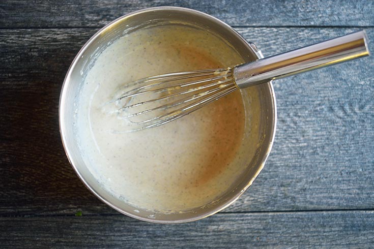 The dressing whisked together in a metal bowl with a whisk.