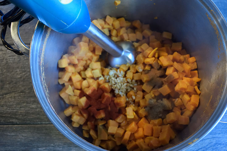 Blending the sweet potatoes and spices with an immersion blender.