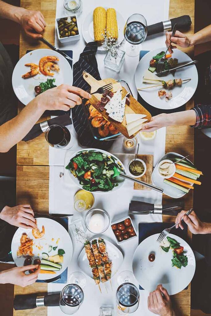 An overhead view looking down on a table at people eating Mediterranean food.