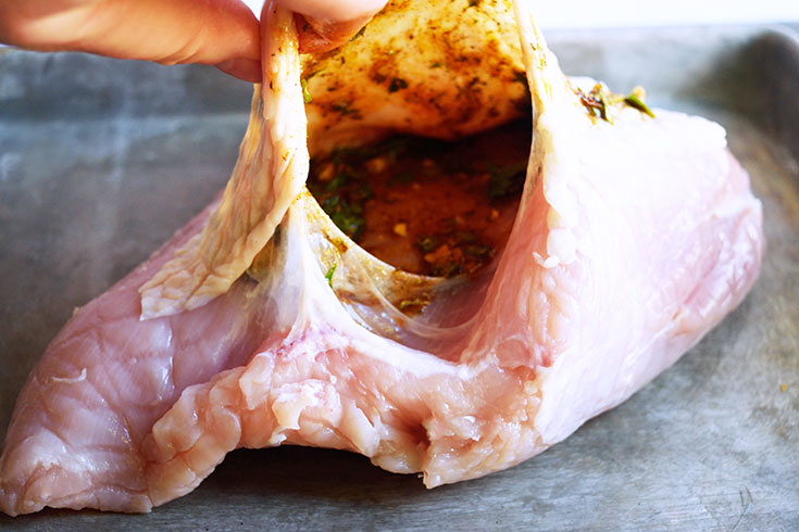 Herbs, spices and oil spread over the turkey breast under the skin.