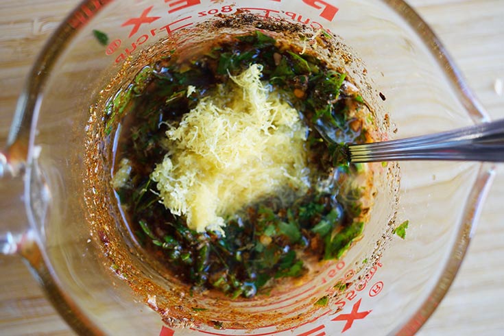 Grated lemon zest and juice added to the seasonings in a measuring cup.